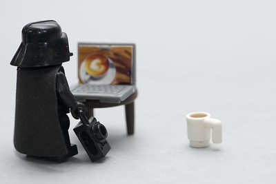 lego Darth Vader looking at a laptop on a stool
