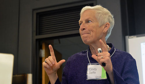 Cindy Selfe gesturing with both hands, holding a marker in her left hand