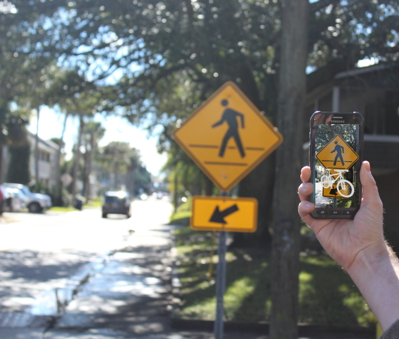 augmented reality image of a ghost bike imposed over a pedestrian crossing sign