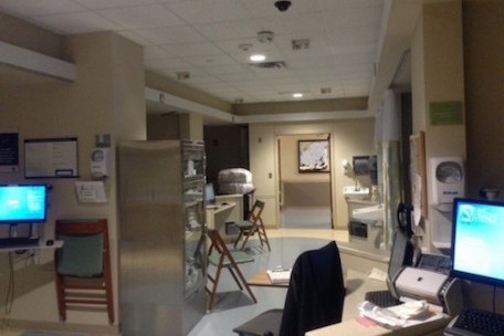 An area of a NICU that's empty, showing empty pods with incubators and a desk with a computer and chair