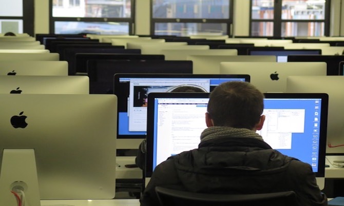 rear-view of man working on computer in a laptop classroom