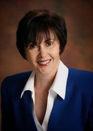 white woman with short dark hair, a white shirt, and a blue blazer