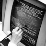 black and white photo: woman in 1969 using a stylus on a old-style monitor