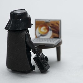 lego Darth Vader looking at a laptop on a stool