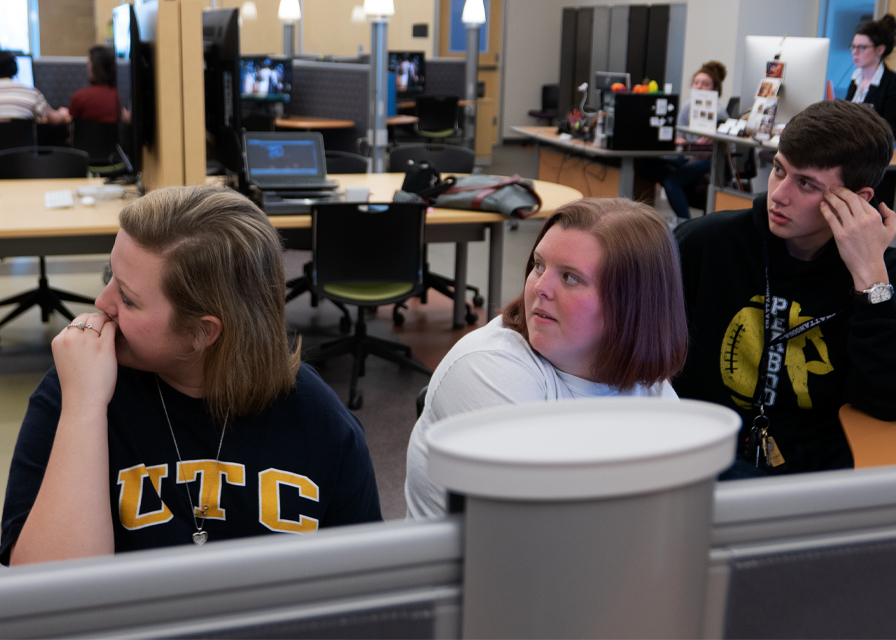 Three students in a classroom, each with their attention drawn to the side