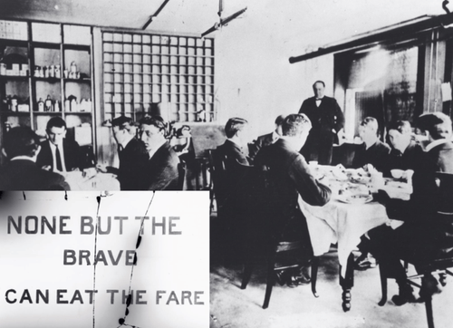 Men at tables with a plaque reading 'NONE BUT THE BRAVE CAN EAT THE FARE.'