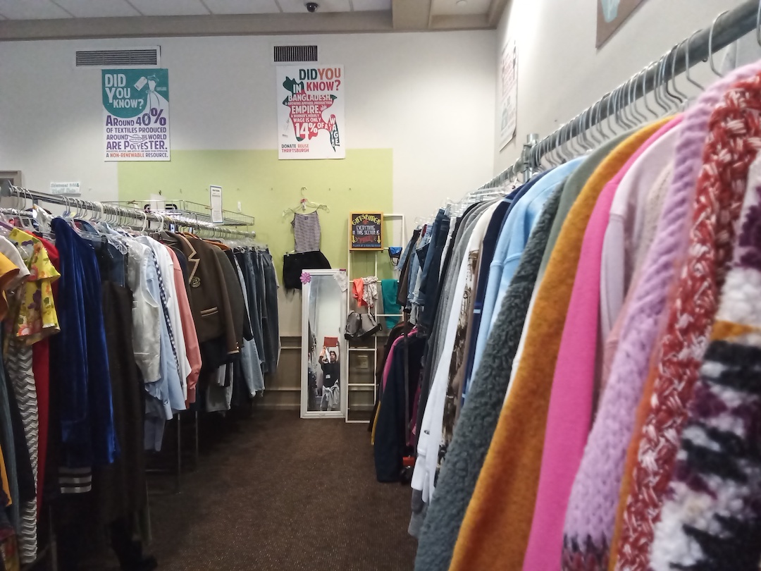 An aisle lined by large racks filled with re-use clothing.
