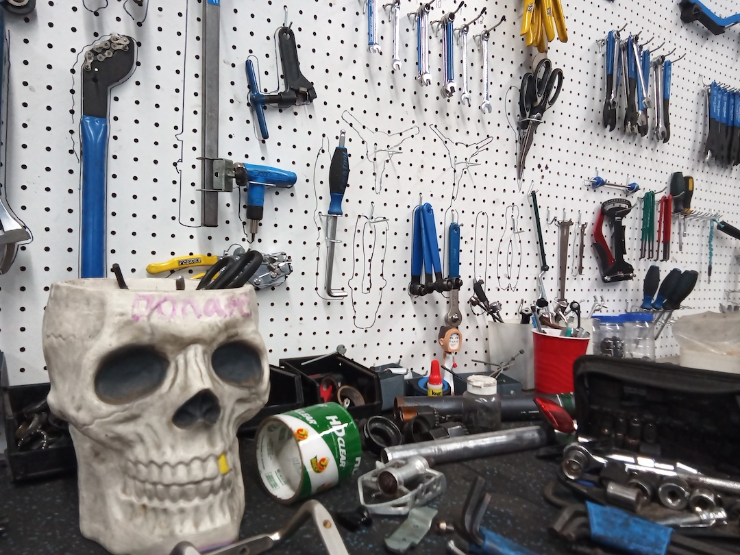 Plastic skull tool container rests atop a messy bike workbench.
