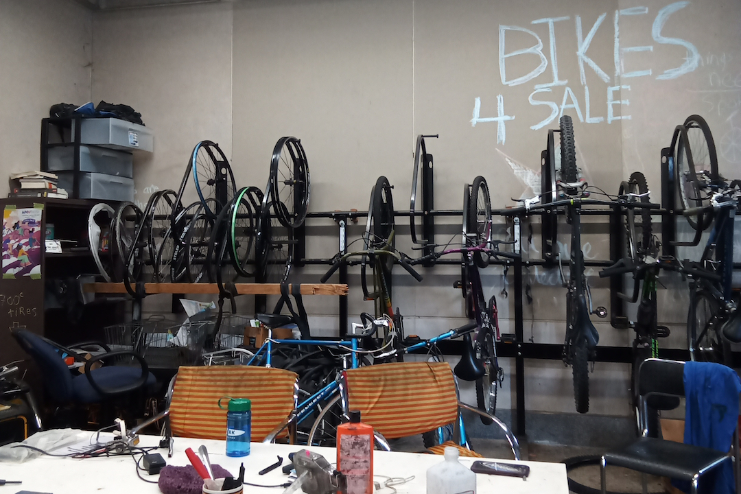 Bikes hanging on a grey wall behind a desk.