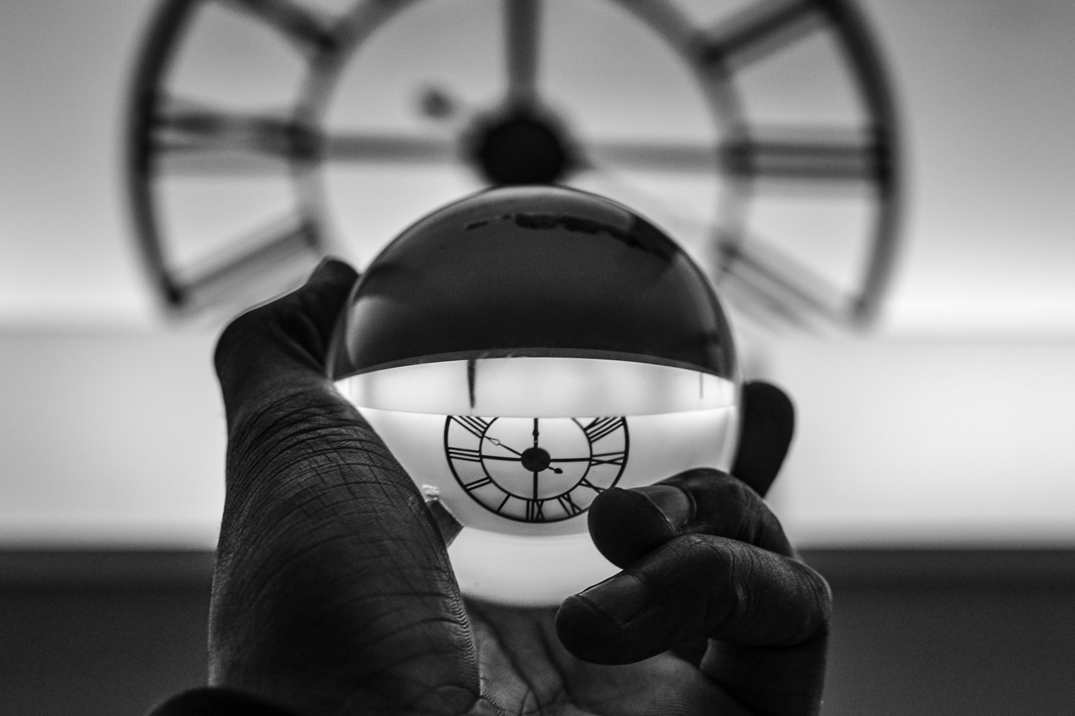 A transparent glass ball inverts the image of a clock face in the background.